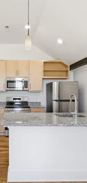 A kitchen with a refrigerator, microwave, and oven.