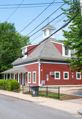 a red building with a grey roof and a white steeple