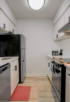 a kitchen with white cabinets and black appliances and a white counter top