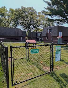 A green sign is on a fence in front of a grassy area.