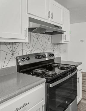 an empty kitchen with white cabinets and a black stove