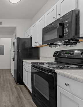 A kitchen with black appliances and white cabinets.