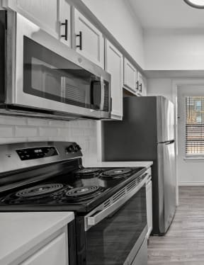 an empty kitchen with white cabinets and stainless steel appliances