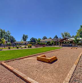A playground with a wooden slide and a brown sandbox.