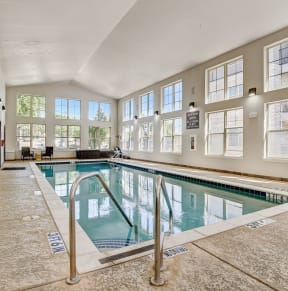 the indoor pool is spacious and has windows and a glass railing around it