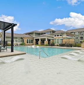 A large outdoor swimming pool with lounge chairs and a pergola.