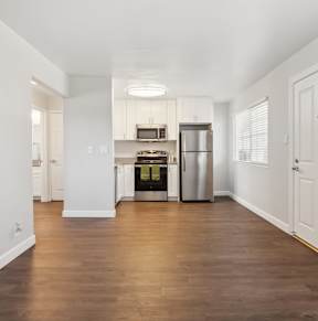 A kitchen with white cabinets and a wooden floor.