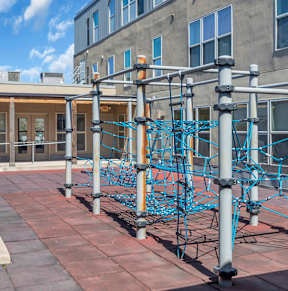 A playground with a blue climbing structure on a brick patio.