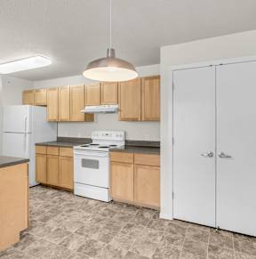 A kitchen with white appliances and wooden cabinets.