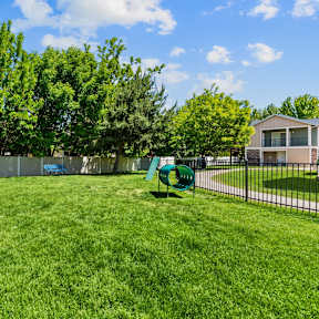 A green lawn with a blue chair and a green bench.