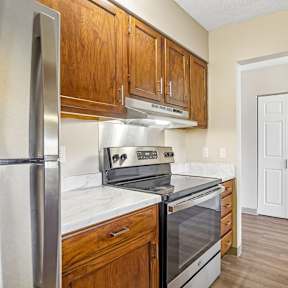 Irvine Park Towers kitchen with stainless steel range, wood cabinetry and doorway to the apartment interior