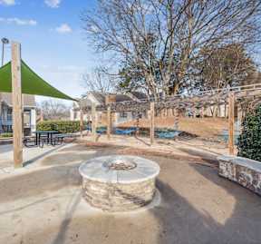 A playground with a green shade sail and a sand pit.