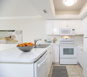 a white kitchen with a sink and a refrigerator