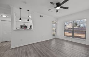 an empty living room with a ceiling fan and a window