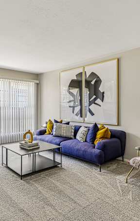 A living room with a blue couch, a fireplace, and a painting on the wall.