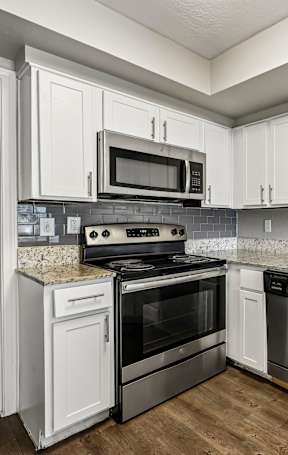 A kitchen with granite countertops and white cabinets.