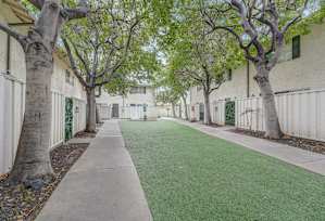 a courtyard with green grass and trees in front of a building