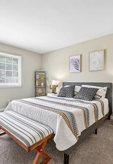 A bedroom with a bed, nightstand, and chair.
