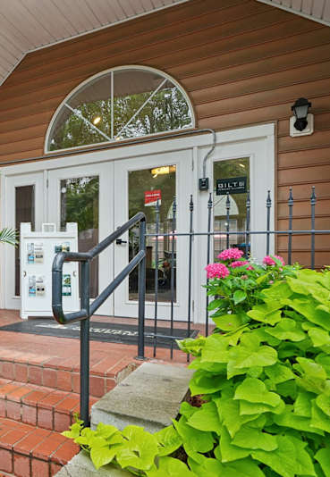 A small building with a white door and a sign on the left.