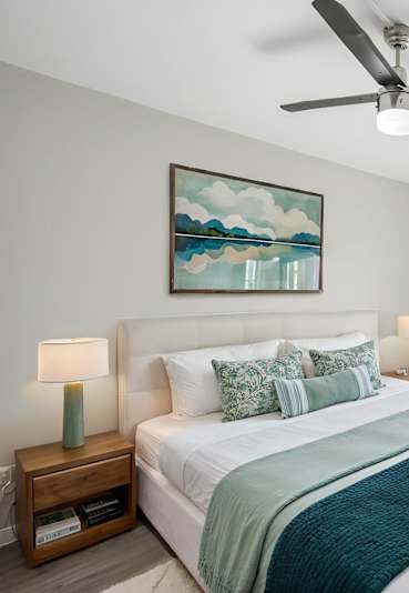 The well-equipped gym at Sono Tempe Apartments features a weightlifting station, Precor machines, dumbbells, and a weight bench, with mirrored walls and colorful carpet tiles.