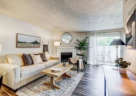 A living room with a couch, a coffee table, and a fireplace.