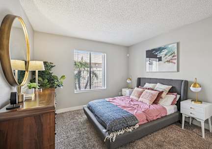 A bedroom with a bed, nightstand, and a mirror.