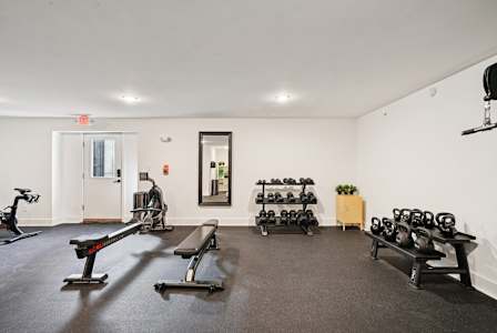 A gym with a variety of equipment including treadmills, weights, and benches.