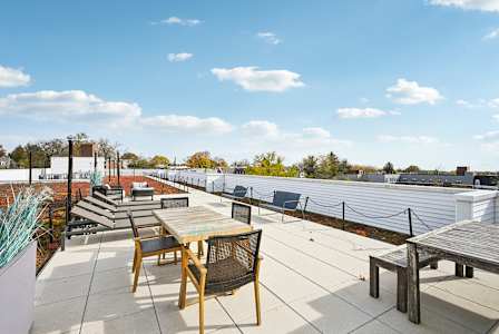 A rooftop patio with a table and chairs.