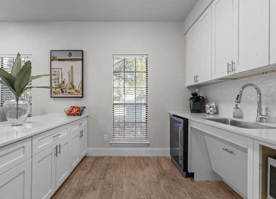 A kitchen with white cabinets and a wooden floor.