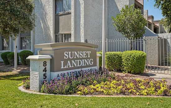 A sign for Sunset Landing Apartments is in front of a building.