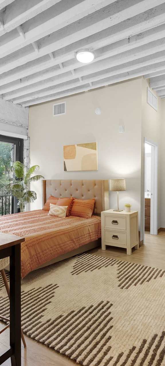 A well-lit, spacious bedroom with a large bed and a dining table with chairs.