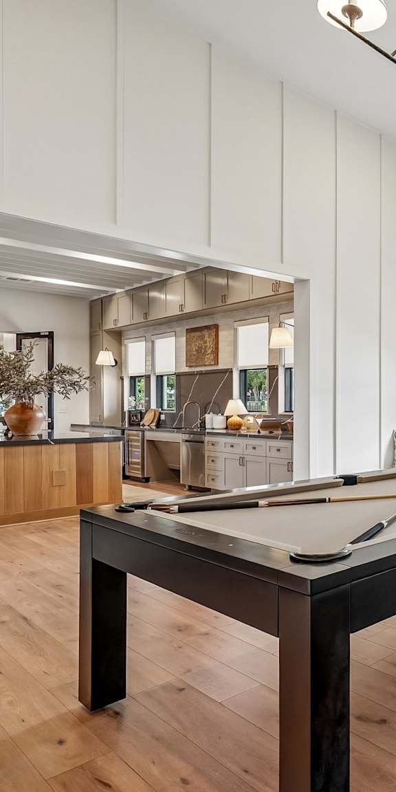 A pool table is in the middle of a room with a window and a picture on the wall.