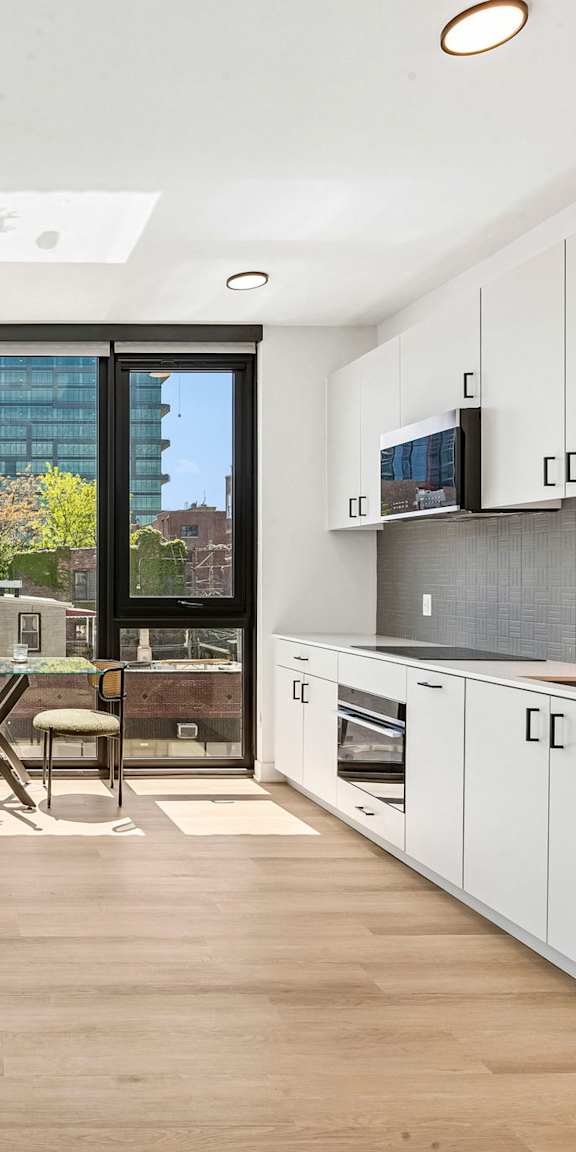 A modern living room with a grey sofa, a white coffee table, and a large window.