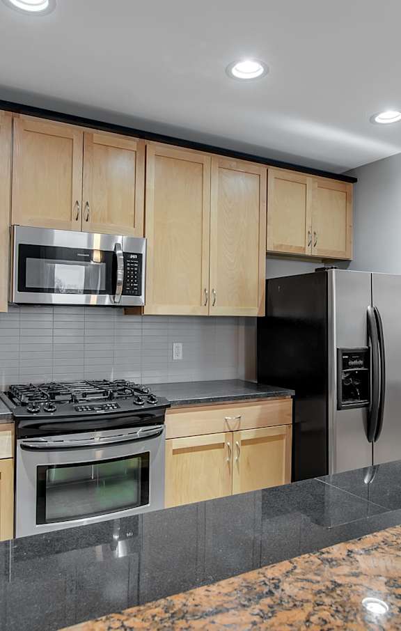 A kitchen with wooden cabinets and a black countertop.