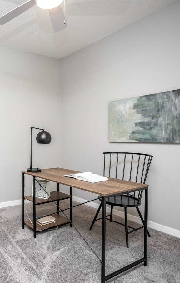 A room with a chair, a table, and a painting on the wall.