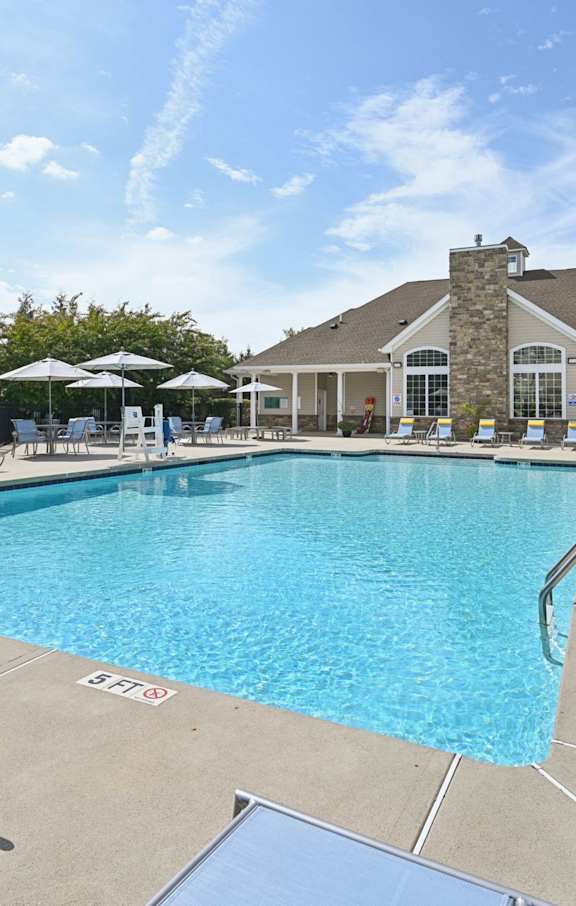 A pool with sun loungers and a building in the background.