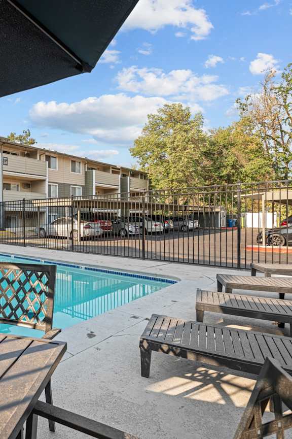 A pool surrounded by wooden deck chairs and umbrellas.