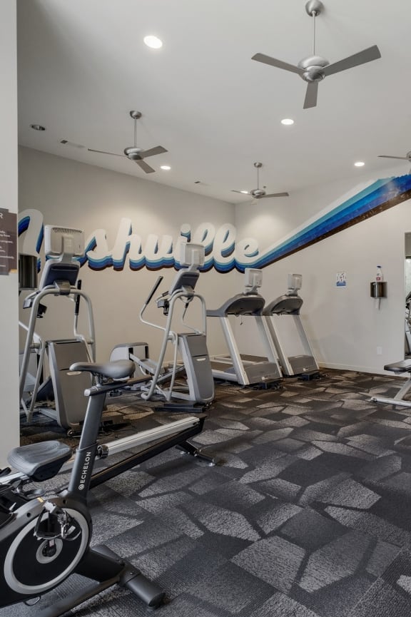 a gym with cardio equipment and weights on the floor