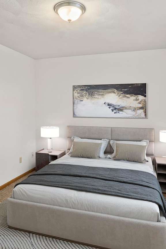 A bedroom with a large bed and a painting on the wall.