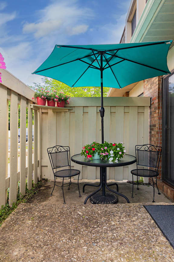 A patio with a table and chairs under an umbrella.