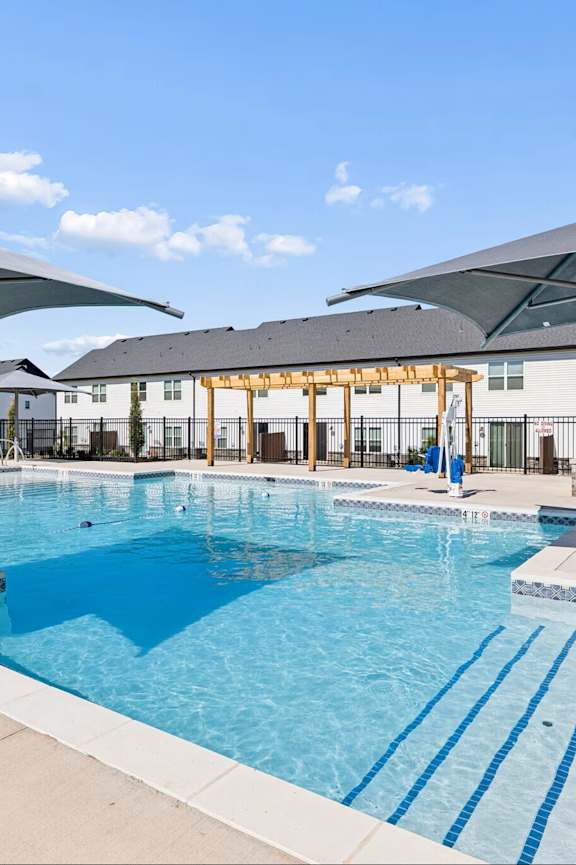 A large outdoor swimming pool with a slide and sun shades.