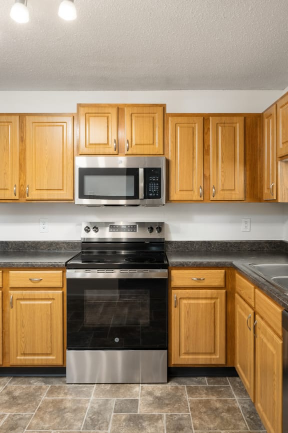 a kitchen with wooden cabinets and stainless steel appliances at Cityscape, St Louis Park, MN, 55416