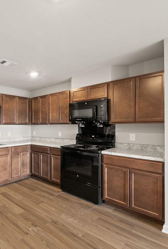 A kitchen with wooden cabinets and black appliances.