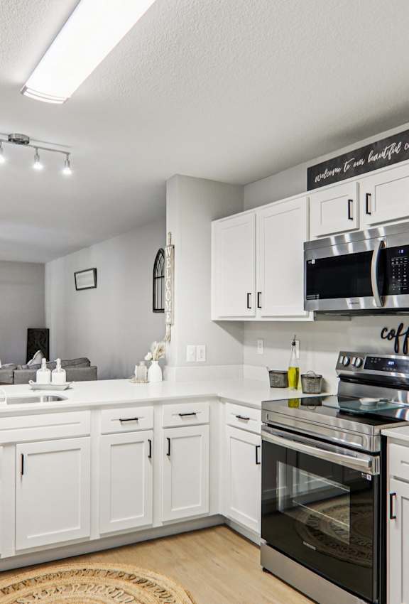 A modern kitchen with white cabinets and stainless steel appliances.