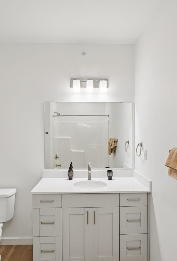 A white bathroom with a toilet, sink, and mirror.