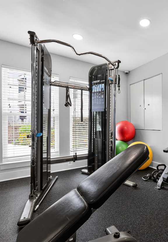 A gym with a variety of equipment including a weight bench, dumbbells, and a mirror.