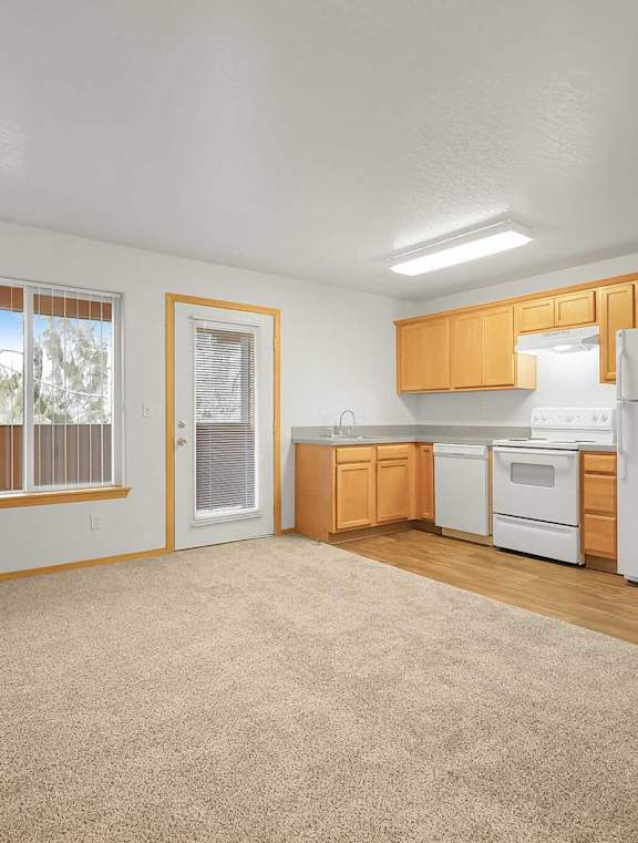 A kitchen with white appliances and wooden cabinets.