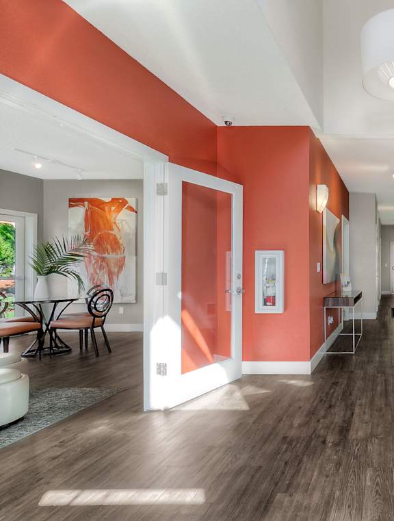 A long hallway with orange walls and wood floors.