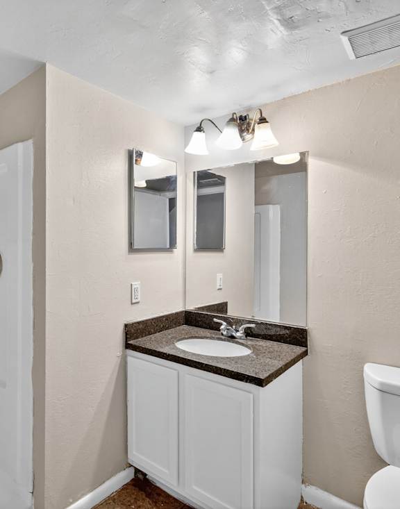 A bathroom with a white toilet, sink, and medicine cabinet.