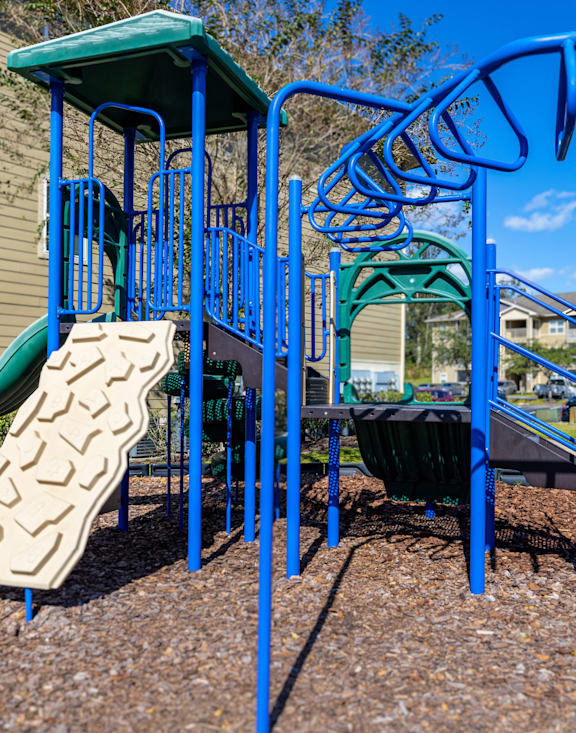 A playground with a blue slide and a green slide.